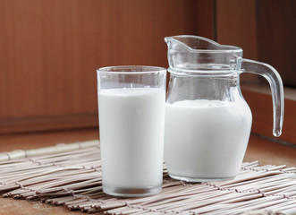 Natural whole milk in a jug and a glass on  the old wooden background