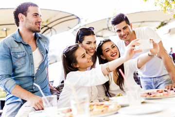 Group of young beautiful people sitting in a restaurant and taki