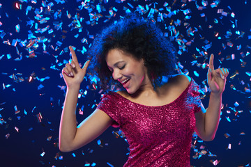Woman dancing on a party over colorful background with confetti