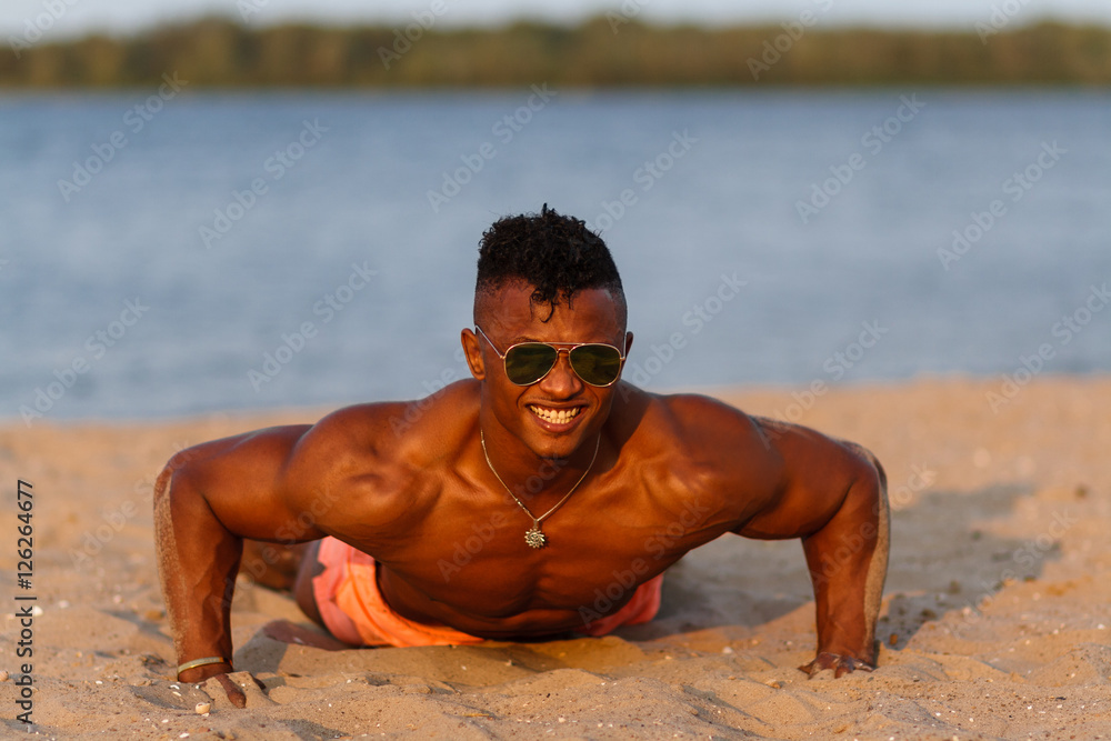 Wall mural muscular young athletic sexy man on the beach with a naked torso in underwear. hot black beautiful g