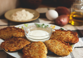 Traditional ukrainian food - deruny. Fried potato pancakes with sour cream on the check tablecloth