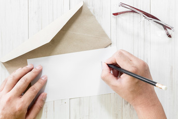 Hands writing letter on wooden table