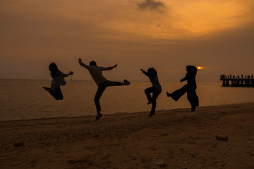 silhouette of friends jumping in sunset