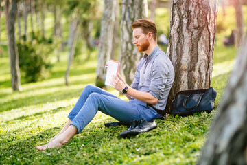 Fototapeta premium Handsome student reading in nature