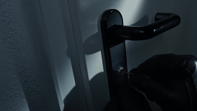 wide angle shot of a burglar picking a lock from an office door