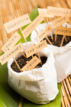 sacs remplis de feuilles s&eacute;ch&eacute;es de th&eacute; et de plantes avec leurs utilisations et bienfaits