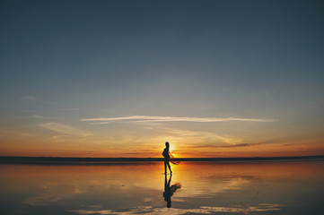 Силуэт беременной женщины на берегу моря на закате