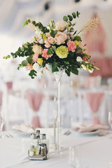 букет цветов в высокой стеклянной вазе на праздничном столе