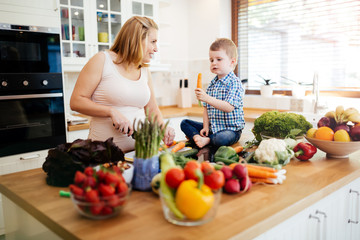 Pregnant woman preparing meal with son