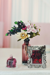 Маленькая цветочная композиция в вазе на столе с красным украшением