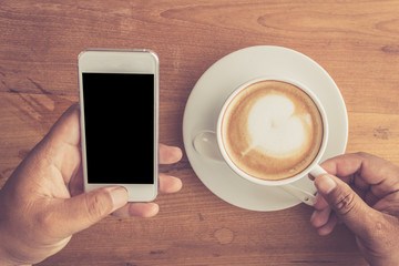 Obraz na płótnie Canvas Man hand use mobile phone and coffee cup vintage tone.
