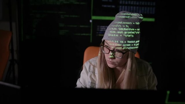 Female hacker working at the computer in dark at night. HD.