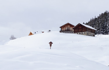 Wegkreuz vor einem Bauernhof tief verschneit