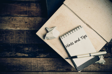 Hints and Tips word on pages sketch book on wood table vertical