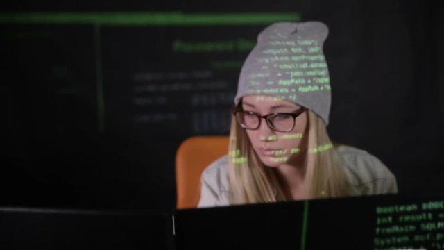 Female hacker working at the computer in dark at night. HD.