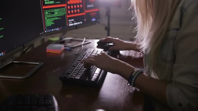 Female hands typing computer code, hacking computer at a dark room. Hacker, programmer at work. HD.