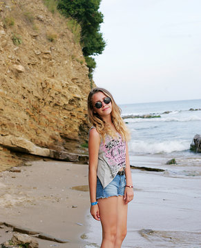 Cute girl in glasses standing on the beach and posing