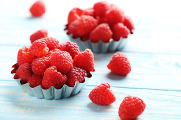 Red raspberries in bowl on a blue wooden table