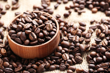Brown roasted coffee beans in bowl on sackcloth
