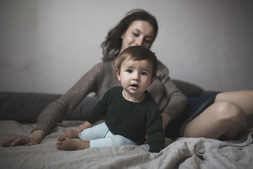 Shaggy young mother playing with baby on  bed,  concept of  comf