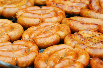 Fresh sausage and hot dogs grilling outdoors on a gas barbecue grill. Closeup of sausage on the grill. Traditional baked polish sausage during the easter