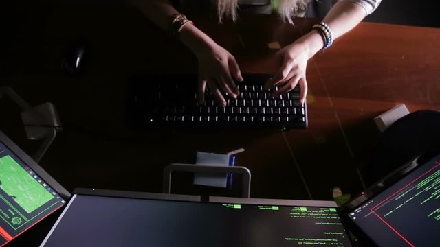 Female hands typing computer code, hacking computer at a dark room. Hacker, programmer at work. HD.