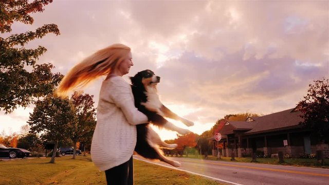 A young woman kidding to his dog, circling her arms, laughing. Australian Shepherd. Slow motion video