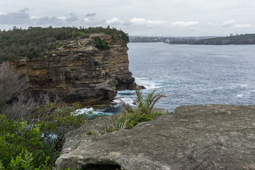 Steep rocky coast of Australia and the blue sea waves breaking on the rocks, the entrance to Sydney Harbour, Sydney