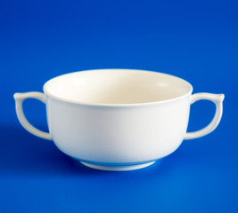 White cup of soup on blue background