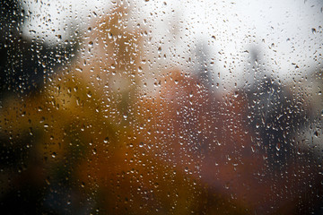 Fototapeta na wymiar raindrops on the glass from the window overlooking the blurred autumn landscape / reflection weather