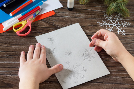 Child sewing needle details paper snowflakes. The child makes a
