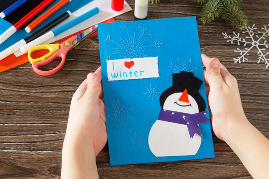 The child makes a greeting card with a snowman. Glue, paper, sci