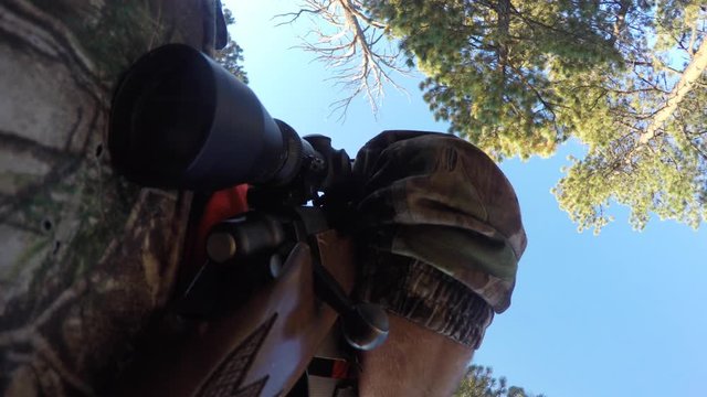 Hunter leans gun up agains a tree