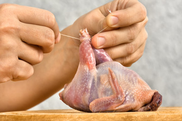 hands preparing quail for roasting