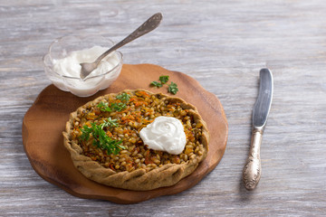 Traditional russian rye pie with pearl barley, pickles and carrots on a wooden table, selective focus