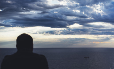 Clouds blue sky and sunlight sunset on horizon ocean Northern Spain Basque Country. Outline looking travel hipster on background seascape dramatic rays sunrise. Relax view waves sea nature