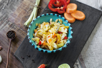 sauerkraut with chilli pepper, bell pepper and lemongrass in plate on black board