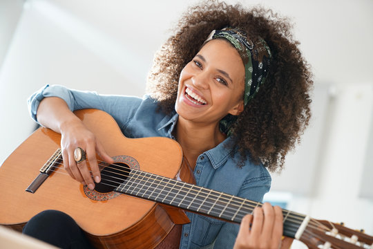 Cheerful girl playing the guitar