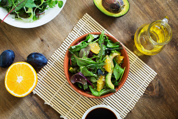 Fresh salad with avocado and orange on the wooden table