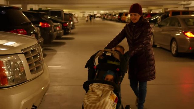 Mother and toddler push baby in stroller through parking garage