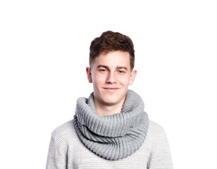 Teenage boy in gray sweater and scarf. Studio shot, isolated.