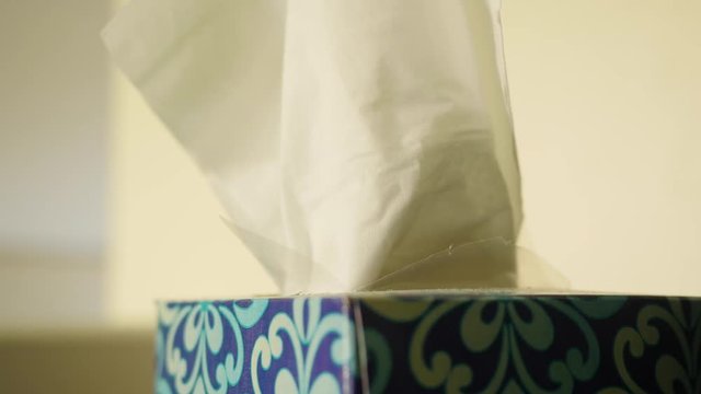 A male hand grabs tissue from a box of kleenex