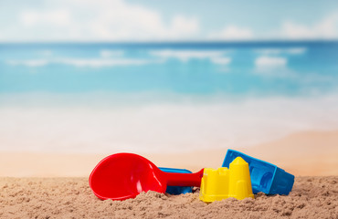 Children's toys castles and shovel in sand against sea.