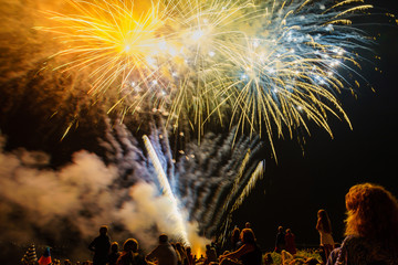 People sitting at the beach an watching the fireworks