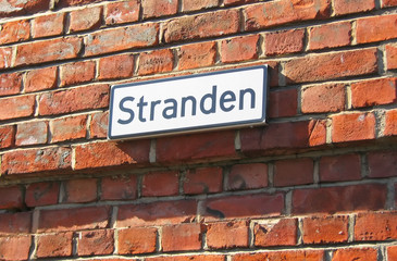 Oslo. Norway. The street name plate on the brick wall. Stranden is name of waterfront promenade in Aker Brygge District, popular touristic place in historical part of the city.