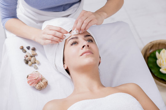 Young woman enjoying facial massage at spa salon