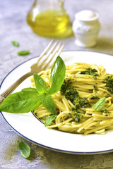 Spaghetti with basil pesto on a white plate.