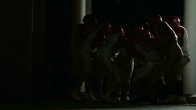 A football team stands in a dark tunnel getting ready before the game