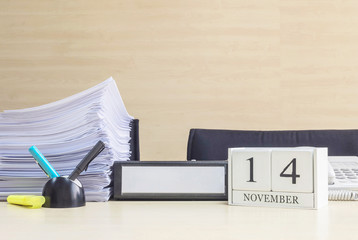 Closeup white wooden calendar with black 14 november word on blurred brown wood desk and wood wall textured background in office room view with copy space , selective focus at the calendar