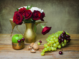Still life with beautiful bouquet of red and white roses placed together in vintage golden tea pot,bunch of grapes, cherries,green apple and walnut on rustic wooden table. - 126295841